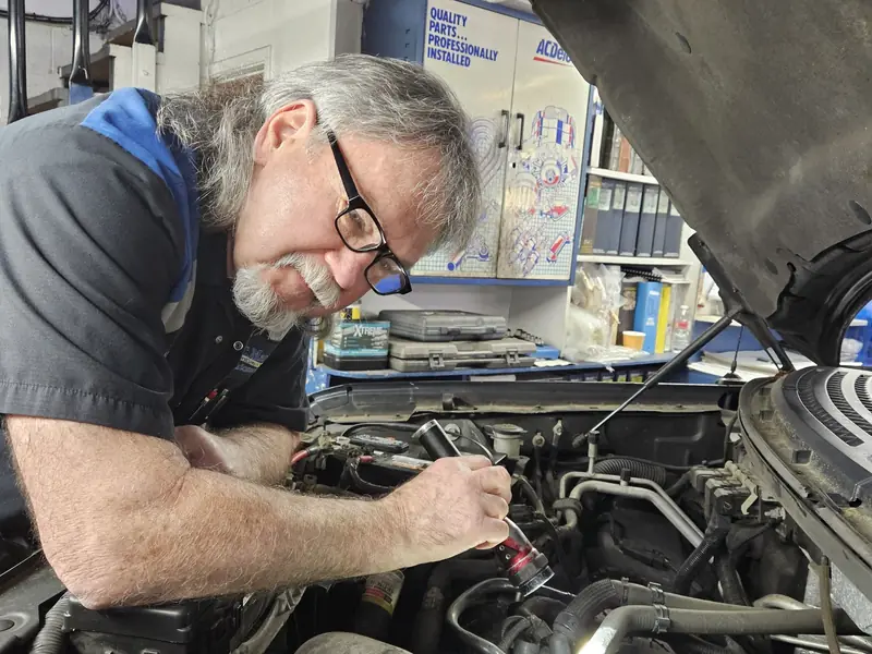 A KC Martin technician with a flashlight working in an engine bay