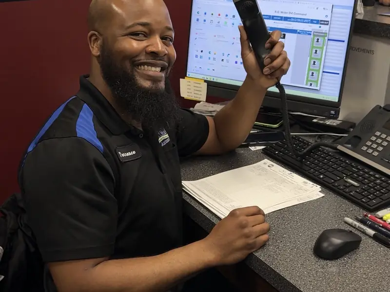 A KC Martin service advisor at the front desk, holding up the phone