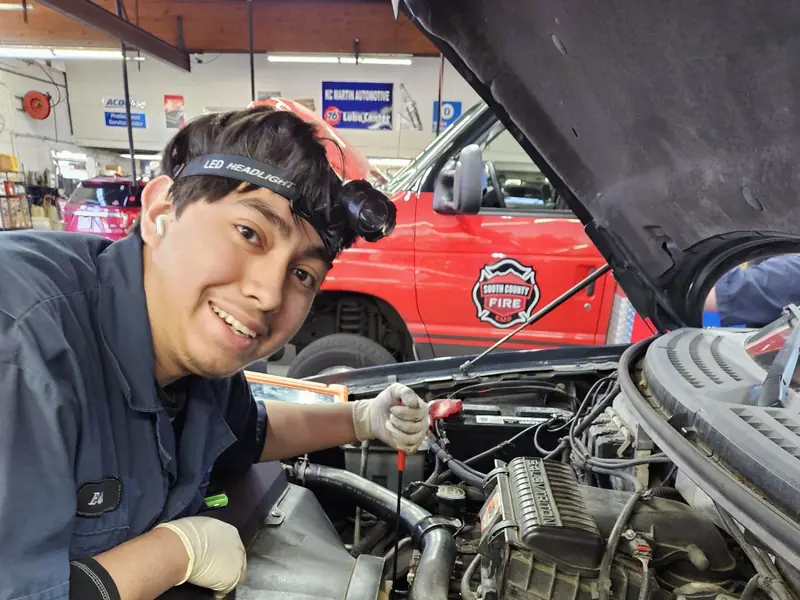A KC Martin technician wearing a headlamp, smiling beside an engine