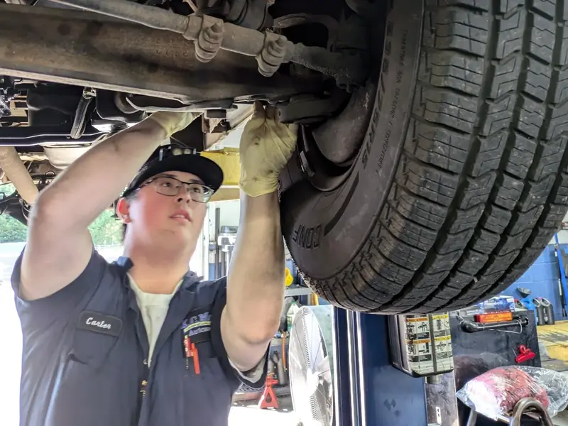 A KC Martin technician working under a truck on the lift