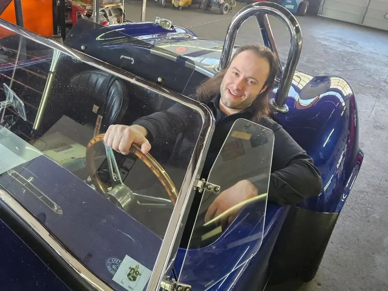 A KC Martin team member at the wheel of a blue roadster in the shop