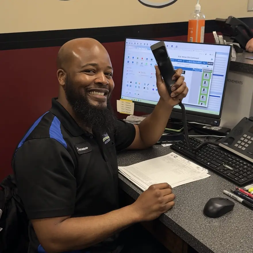 A KC Martin service advisor at the front desk, holding up the phone