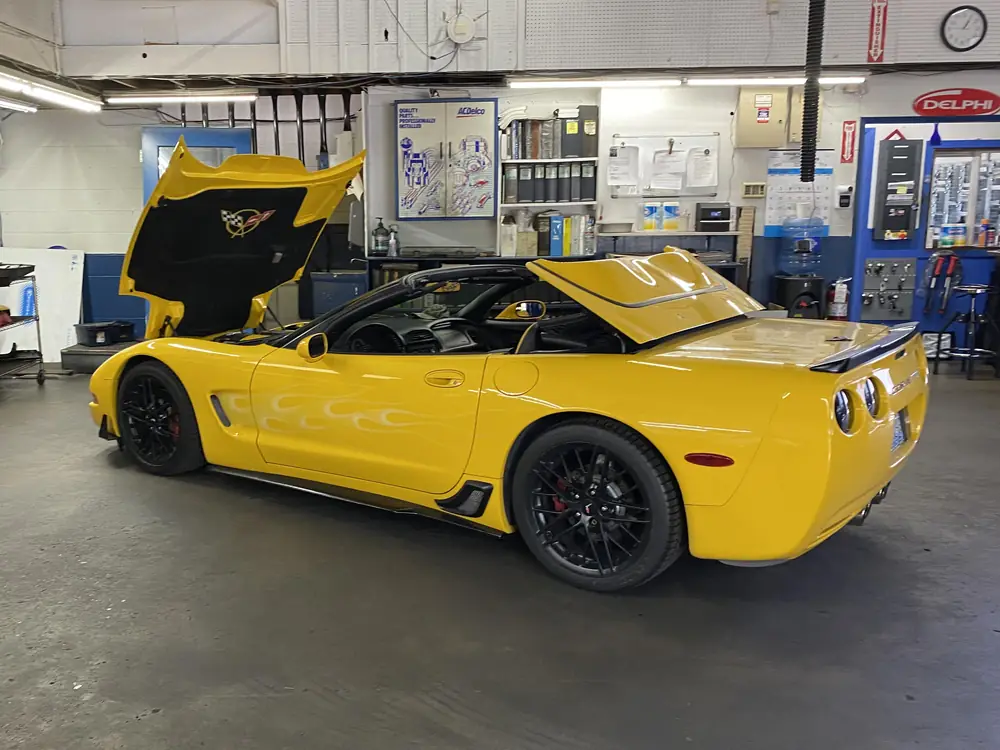 A yellow Chevrolet Corvette convertible with its hood open inside the KC Martin shop in Lynnwood