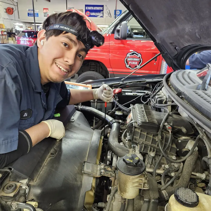 A KC Martin technician at an engine, with the radiator hose and coolant tank in view