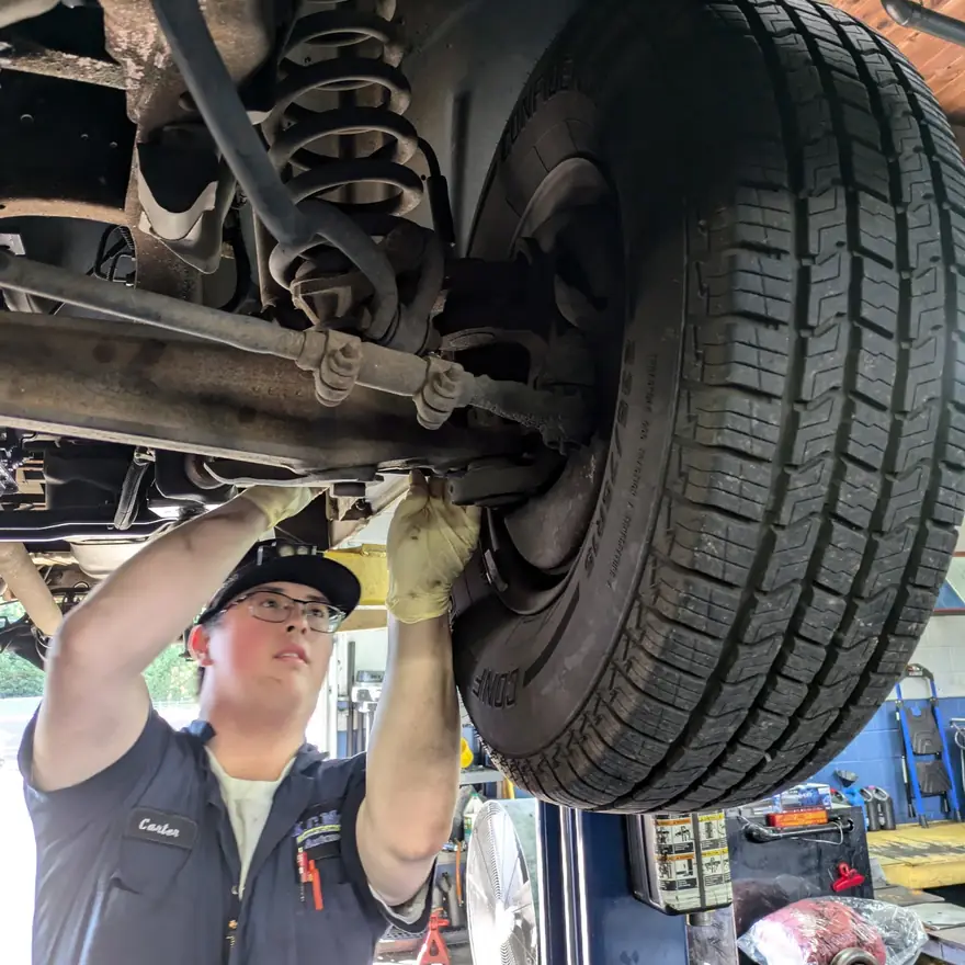 A KC Martin technician working on the front suspension of a truck on the lift