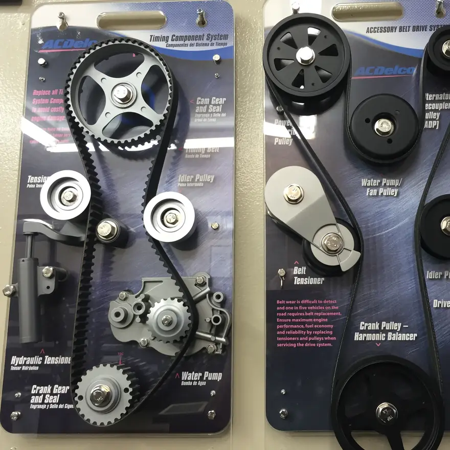 A timing belt, gears, tensioner and water pump on a display board at KC Martin